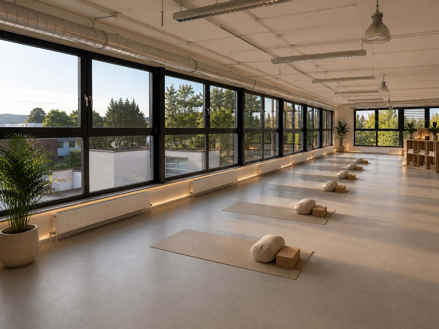 Helle, offene Studiofläche mit Fensterband, Yogamatten und Bolstern